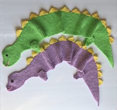 three crocheted dinosaurs sitting next to each other on top of a white surface