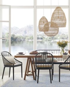 a dining room table and chairs in front of large windows