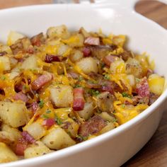 potato hash browns loaded with bacon and cheese in a white casserole dish on a wooden table