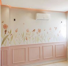 an air conditioner mounted to the side of a wall in a room with flowers painted on it