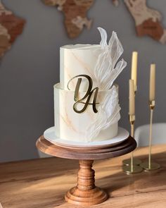 a three tiered cake with white icing and gold lettering on top, sitting on a wooden stand