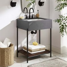 a bathroom sink sitting under a mirror next to a plant