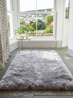 a living room with a large window and a rug on the floor in front of it