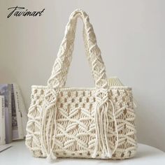 a crocheted white bag sitting on top of a table next to a book