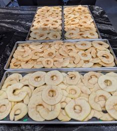 three trays filled with different kinds of donuts on top of a black table