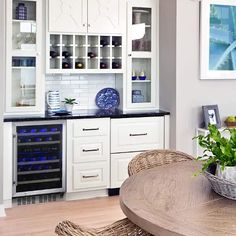 a kitchen with white cabinets and black counter tops is pictured in this image, there are wicker chairs around the table