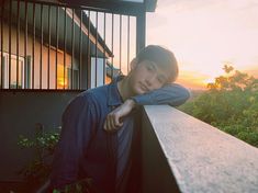 a young man leaning on the edge of a balcony