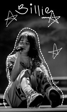 a woman sitting on the ground while holding a microphone to her mouth and singing into a microphone