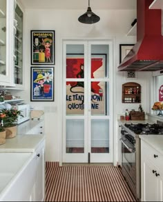 a kitchen with red and white striped flooring next to an open glass front door