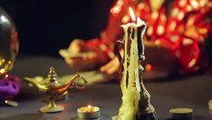 a lit candle sitting on top of a table next to some candles and other decorations