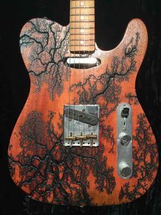 an orange and black guitar with trees on it