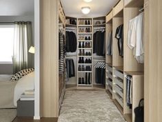 a walk - in closet with clothes and shoes on shelves next to a bed,