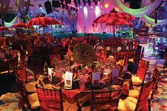 a banquet hall with tables and chairs covered in red cloths, decorated with umbrellas