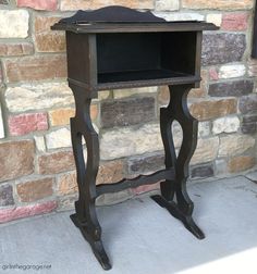 an old wooden table with a black shelf on it's side and brick wall in the background