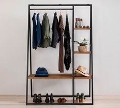 an iron and wood clothing rack with clothes hanging on the rails, shoes and hats