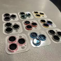 several different colored buttons sitting on top of a silver table with black and white circles