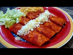 a red plate topped with meat and rice covered in sauce next to lettuce