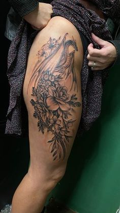 a woman with a dragon tattoo on her thigh is sitting next to a green wall