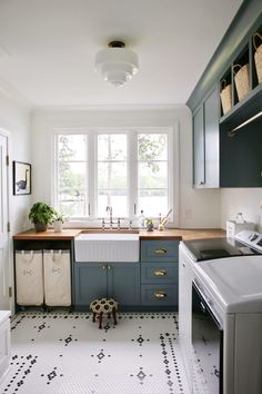 a kitchen with blue cabinets and white walls, an oven, washer and dryer