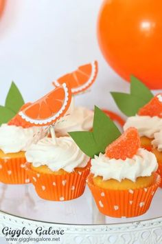 cupcakes decorated with orange slices and garnishes on a glass plate