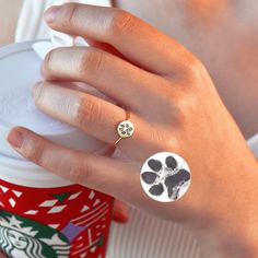 a woman's hand holding a starbucks cup with a dog paw ring on it