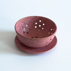 two pink ceramic bowls sitting side by side on top of each other with holes in them