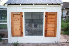 a chicken coop with wooden shutters and chickens in it