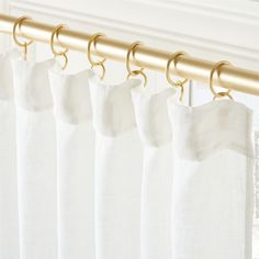 white curtains with gold hardware hanging on a rod