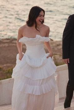 a woman in a white dress standing next to a man