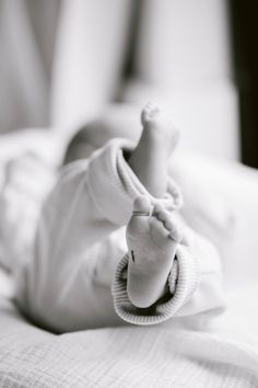 a black and white photo of a baby laying on it's back with its hand in the air