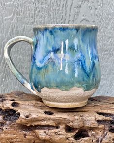 a blue and white mug sitting on top of a piece of wood