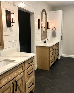 a large bathroom with two sinks, mirrors and lights on the side of the wall