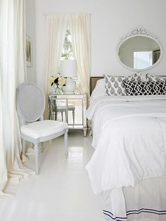 a bedroom with white furniture and curtains