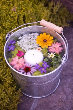 a metal bucket filled with flowers and a candle