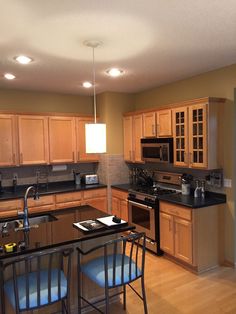 a kitchen with wooden cabinets and black counter tops next to an island in the middle