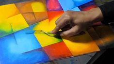 a person is using scissors to cut out colorful squares on a piece of art paper