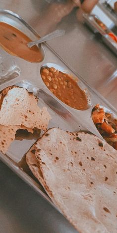 several different types of food are on a metal tray, including tortillas and beans