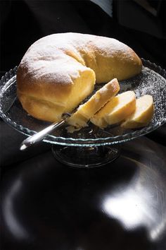 bread and butter on a glass plate with a silver serving utensil in the middle