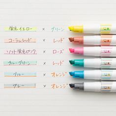 four pens sitting on top of each other next to an open notebook with japanese writing