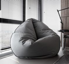 a bean bag chair sitting on top of a white floor next to a window covered in blinds