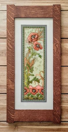 a painting hanging on the side of a wooden wall next to a wood frame with flowers and leaves