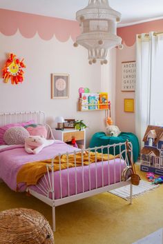 a child's bedroom with pink and yellow walls, white metal bed frame, wicker baskets on the floor