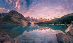 a lake surrounded by rocks and mountains under a cloudy sky