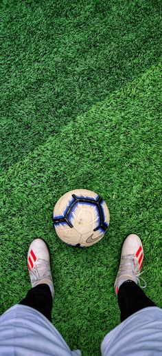 a person standing next to a soccer ball on top of a green grass covered field