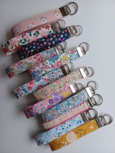 six key fobs are lined up on a white surface with flowers and polka dots