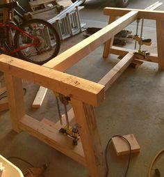 a wooden bench being built in a garage next to a bike and other tools on the floor