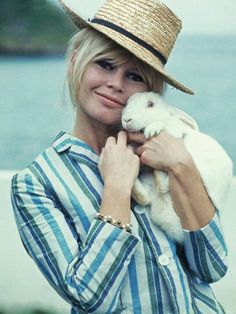 a woman wearing a hat holding a small animal