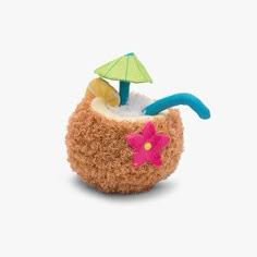 a stuffed animal in a coconut shell with an umbrella on the top and some sand inside