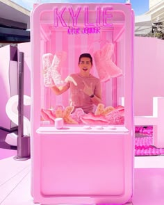 a man standing in front of a pink ice cream kiosk with wings on it