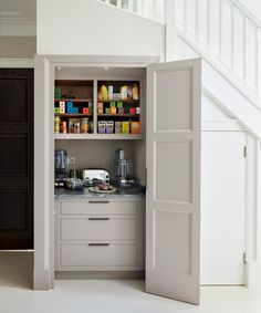 an open pantry door in the middle of a kitchen with coffee maker and other items